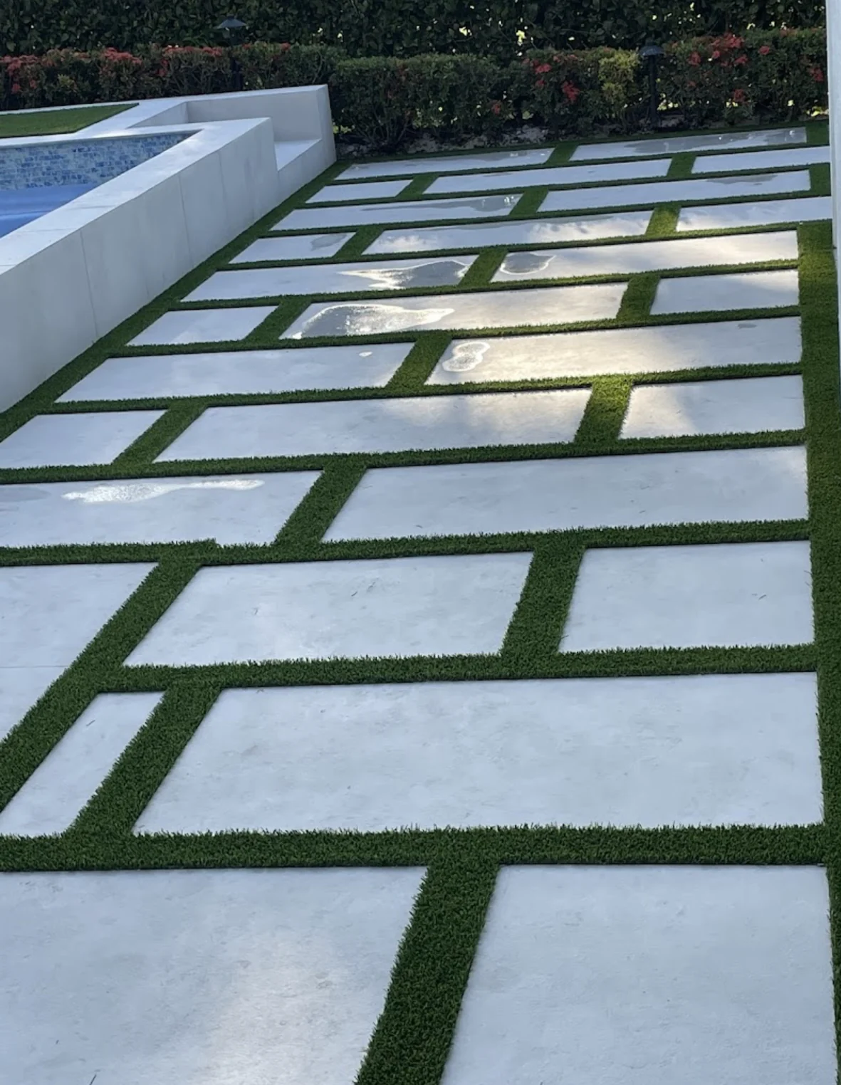 Artificial turf installed between large-format pavers in a documented Jupiter backyard