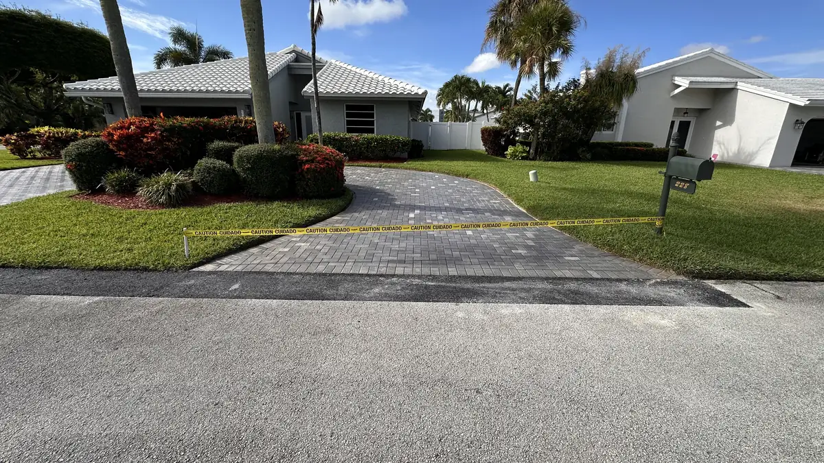 Finished asphalt edge repair connecting two residential paver driveways