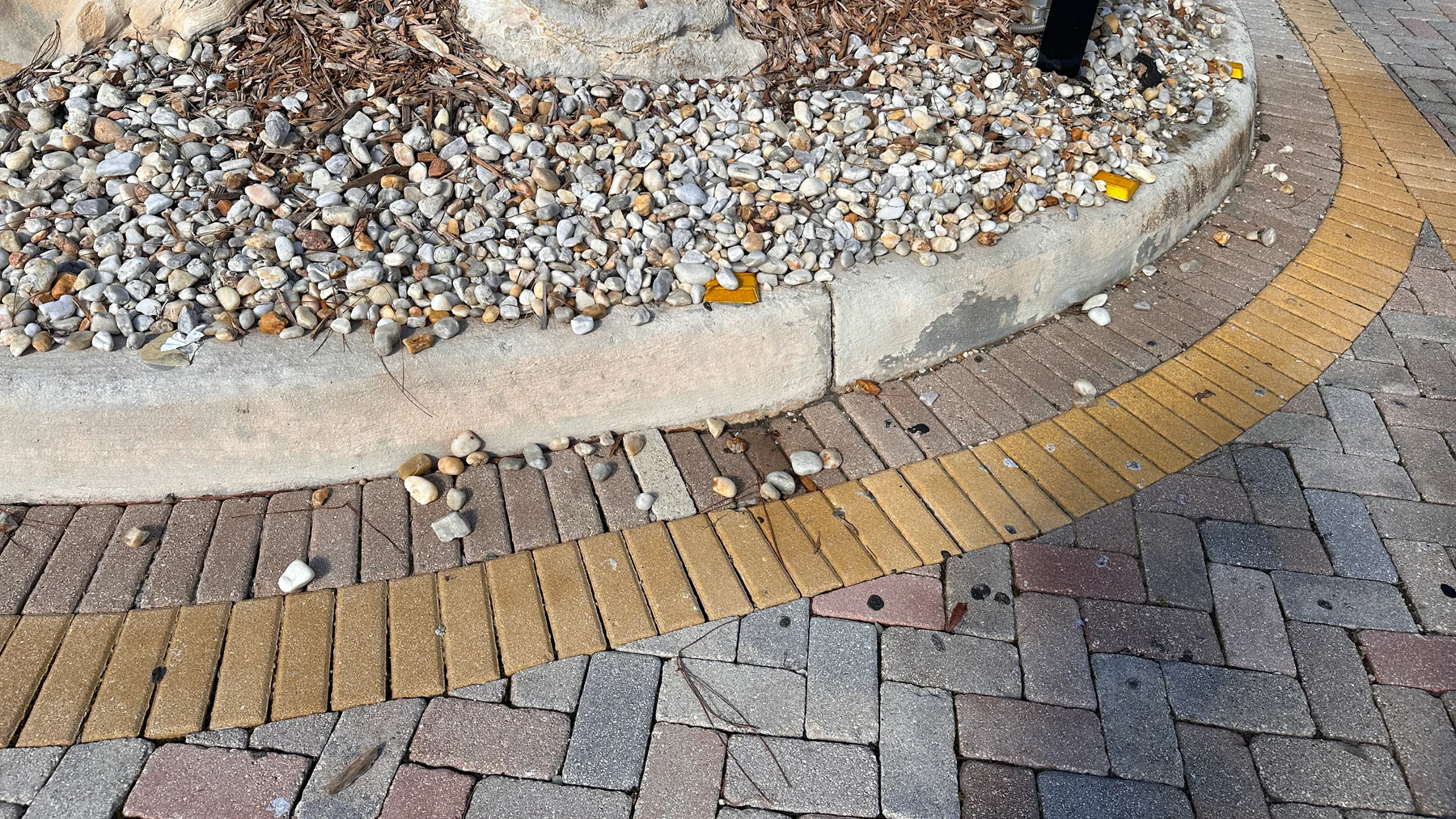 Broken concrete pavers along a landscape border in Palm Beach County