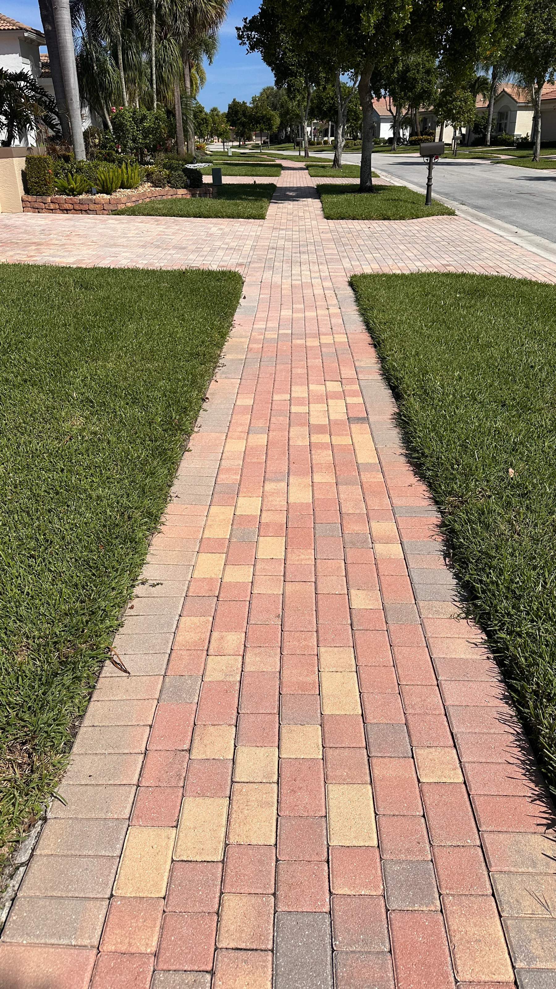 Brick paver walkway beside a landscaped Palm Beach County entrance