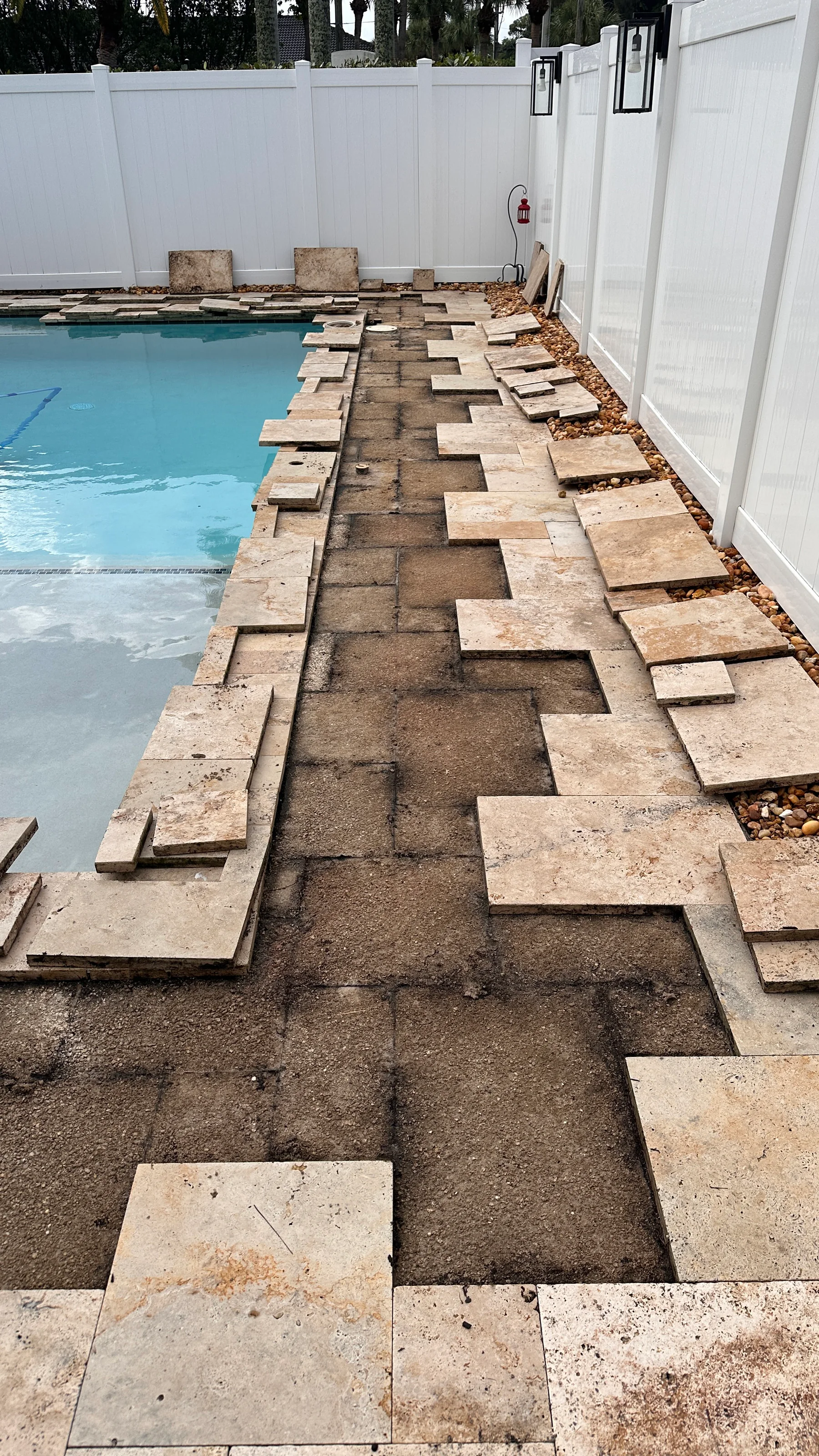Exposed pool deck support area with existing pavers staged for reuse