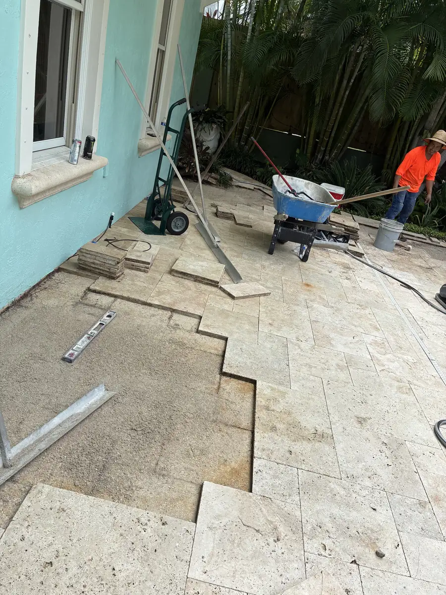 Travertine pool deck pavers being lifted and relaid during repair