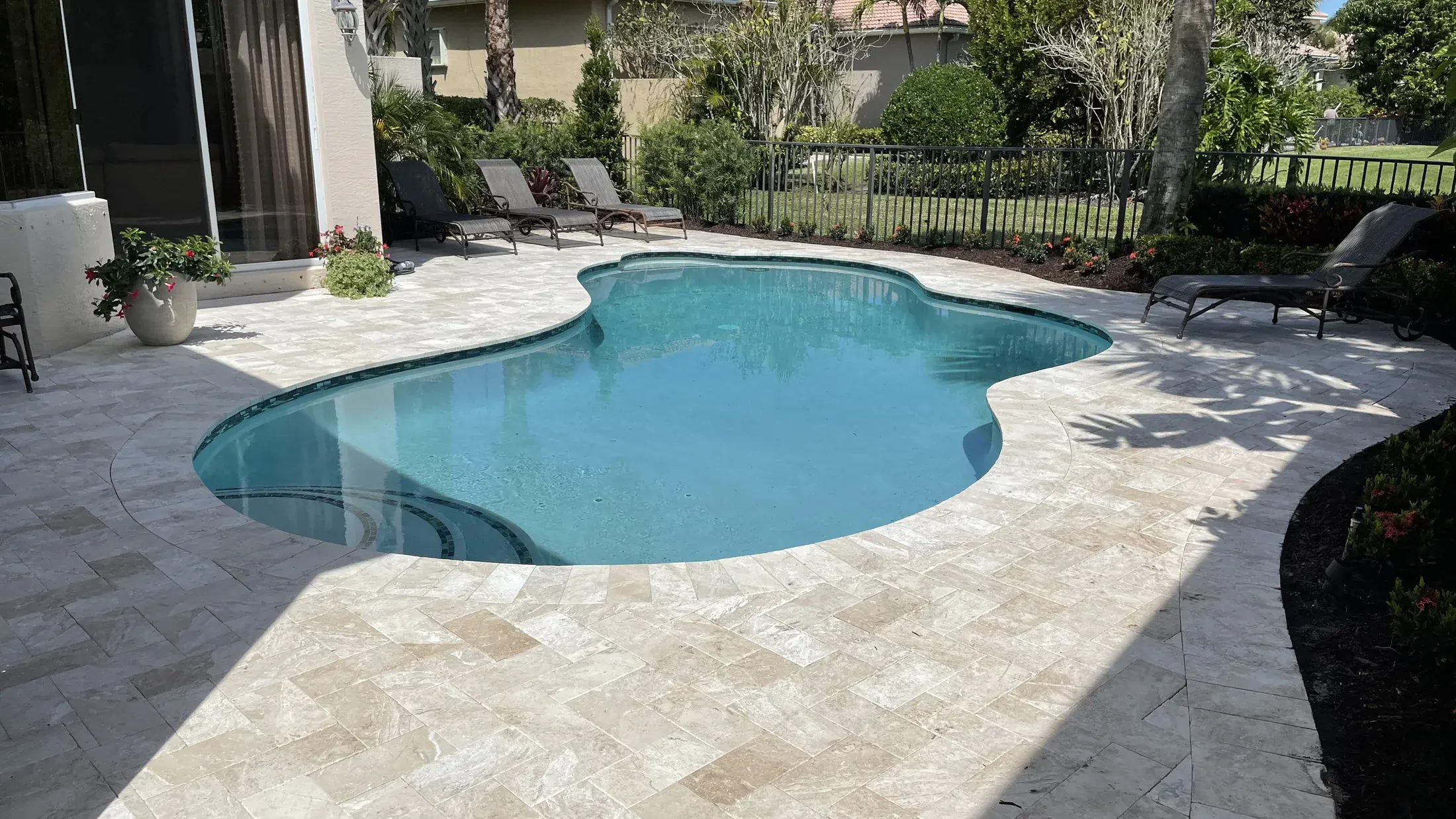 Freeform pool with refreshed plaster and light natural stone surround