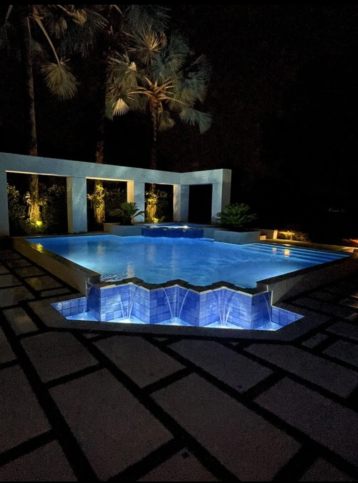 Illuminated Jupiter poolside patio with pavers and artificial turf after dark