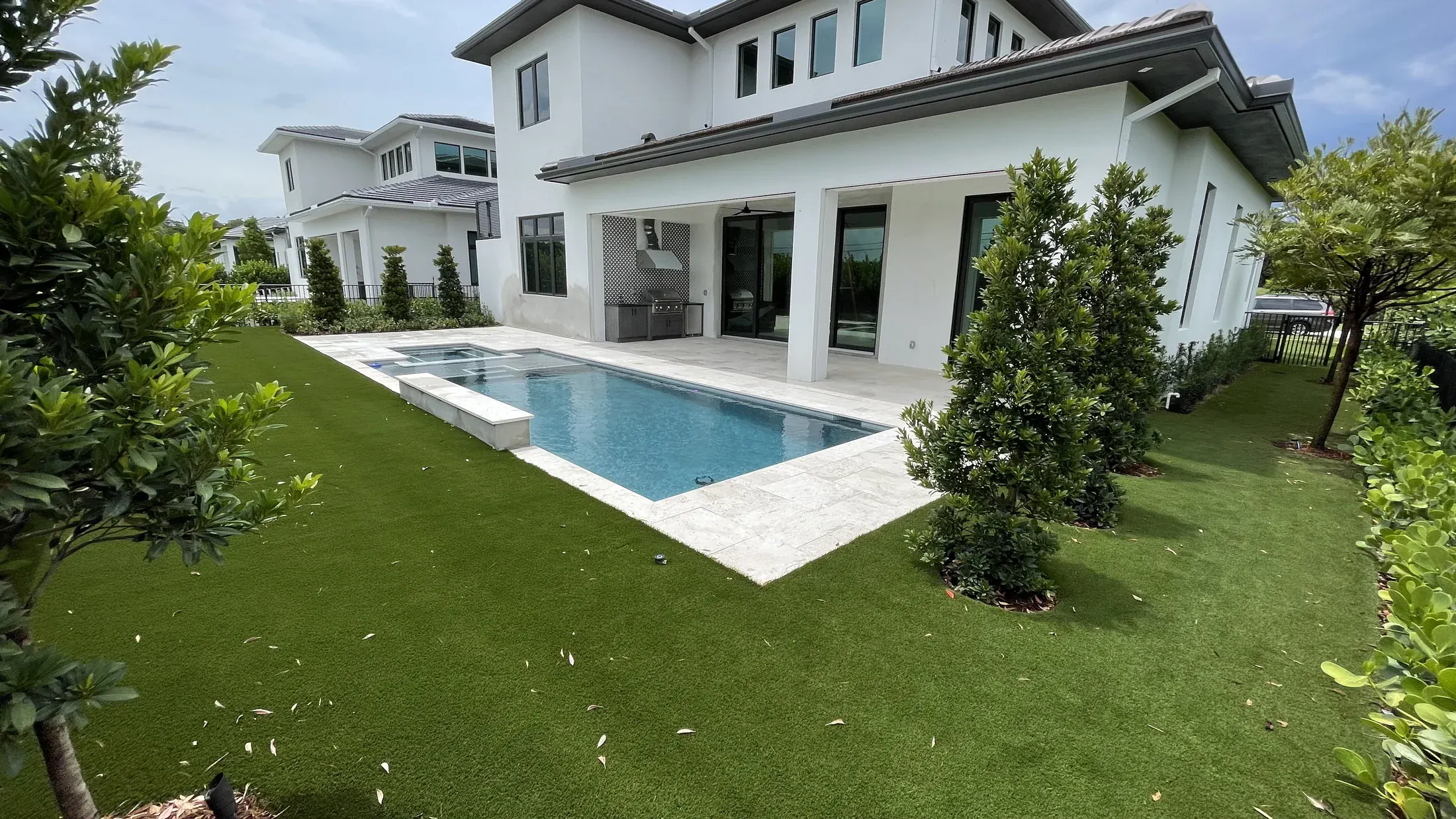 Complete backyard pool remodel with travertine coping and artificial turf